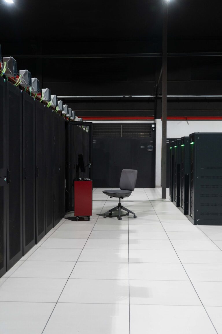 A system administrator’s workstation within a data processing centre with rack cabinets and servers inside.